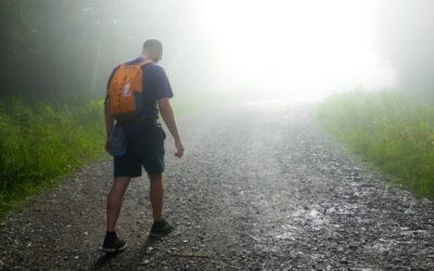a man with a backpack walking down a foggy road