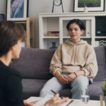 a woman sitting on a couch talking to another woman