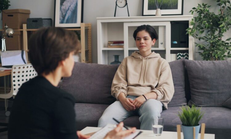 a woman sitting on a couch talking to another woman